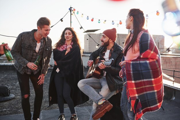 Conmovedora pieza de arte musical. Fiesta en la azotea con alcohol y guitarra acústica en un soleado día de otoño