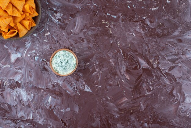 Cono de chips en un bol con yogur en un bol, sobre la mesa de mármol.