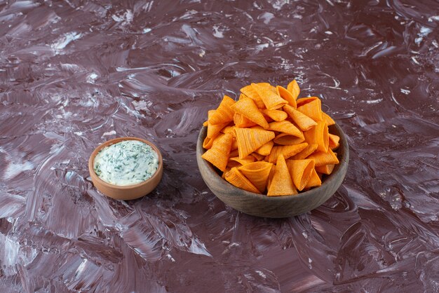 Cono chips en un bol con yogur en un bol sobre la superficie de mármol