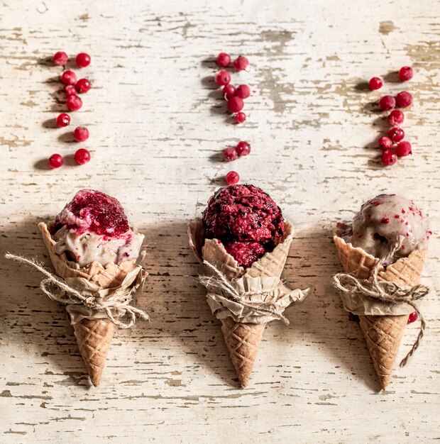 Cono de galleta de helado con bayas sobre fondo de madera