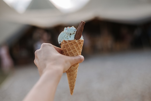 Un cono de helado con bola de helado con sabor azul con una rodaja de chocolate