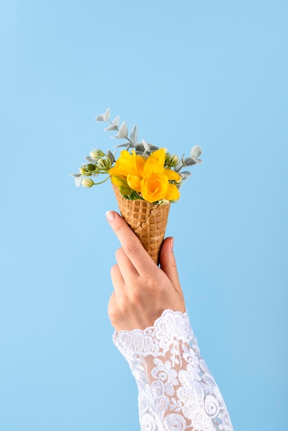 Foto gratuita cono de helado con flores y fondo azul.