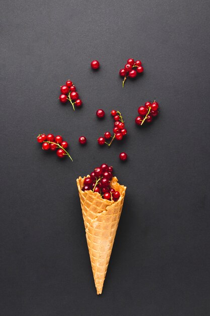 Cono de helado plano con grosellas rojas.