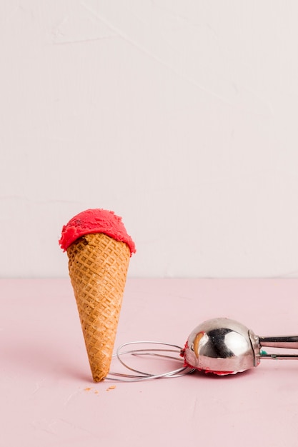 Cono de helado rojo con pala.