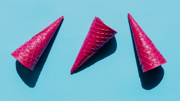 Foto gratuita conos de galleta rosa brillante en superficie azul