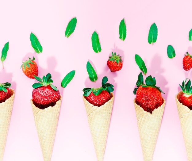 Conos de helado crujientes con fresa en superficie clara