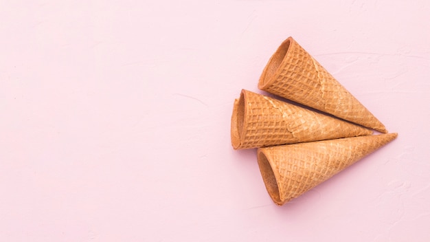 Conos de helado crujientes de la galleta en superficie rosada