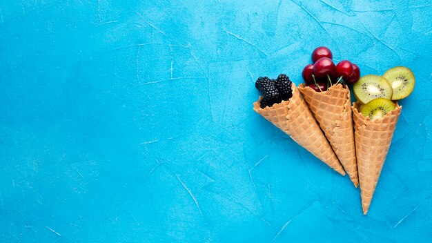 Conos de helado planos con bayas y espacio de copia.