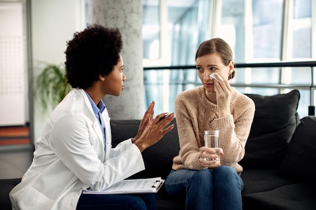 Consejero afroamericano hablando con una mujer llorando durante una sesión de psicoterapia