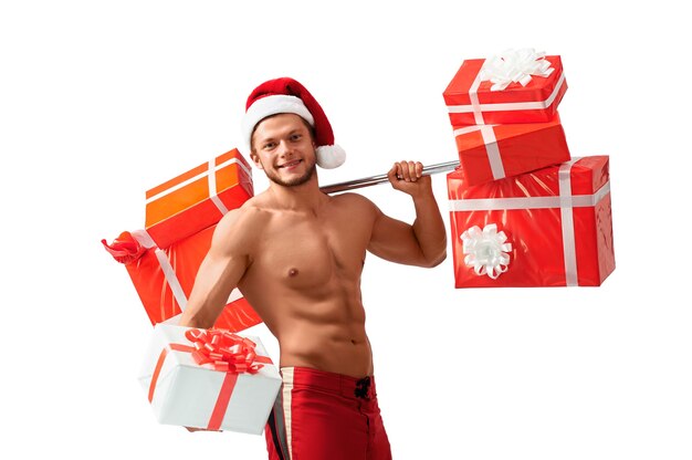 Consejos de fitness de Santa. Retrato de un Papá Noel desgarrado sin camisa que ofrece una gran caja de regalo mirando hacia otro lado sonriendo felizmente, 2018, 2019.