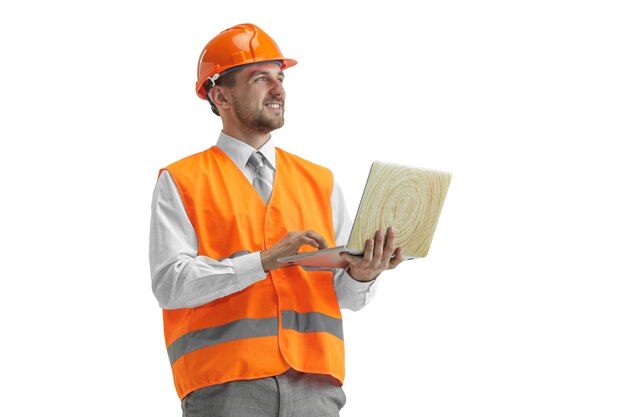 El constructor con un chaleco de construcción y un casco naranja con portátil. Especialista en seguridad, ingeniero, industria, arquitectura, gerente, ocupación, empresario, concepto de trabajo