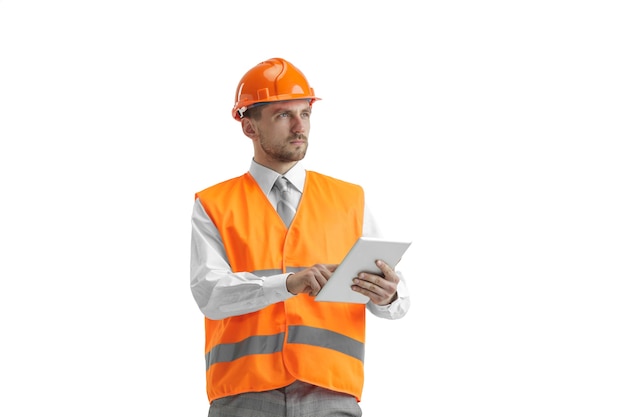 El constructor con un chaleco de construcción y un casco naranja con tableta. Especialista en seguridad, ingeniero, industria, arquitectura, gerente, ocupación, empresario, concepto de trabajo