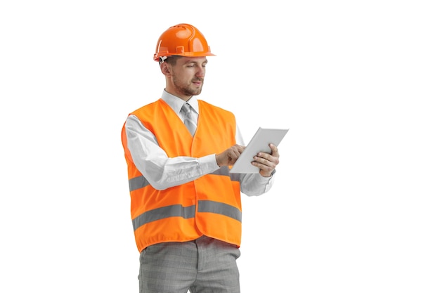 El constructor con un chaleco de construcción y un casco naranja con tableta.