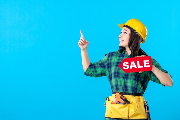 Constructor femenino de la vista frontal que sostiene la escritura roja de la venta en azul