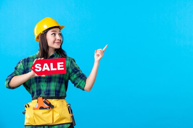 Constructor femenino de la vista frontal que sostiene la escritura roja de la venta en azul