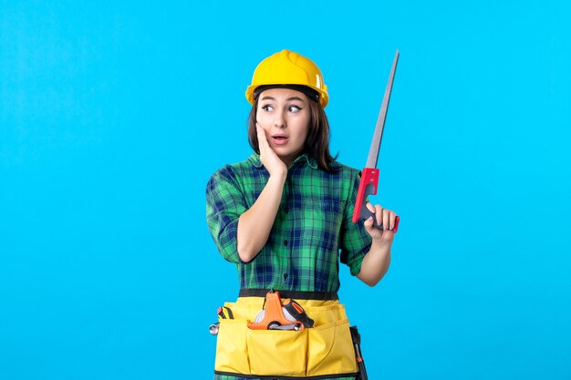 Constructor femenino de la vista frontal que sostiene la sierra pequeña en azul