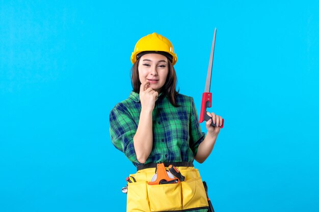 Constructor femenino de la vista frontal que sostiene la sierra pequeña en azul