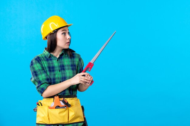 Constructor femenino de la vista frontal que sostiene la sierra pequeña en azul