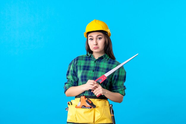 Constructor femenino de la vista frontal que sostiene la sierra pequeña en azul