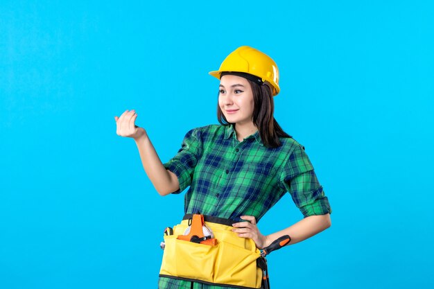 Constructor femenino de vista frontal en uniforme y casco llamando a alguien en azul