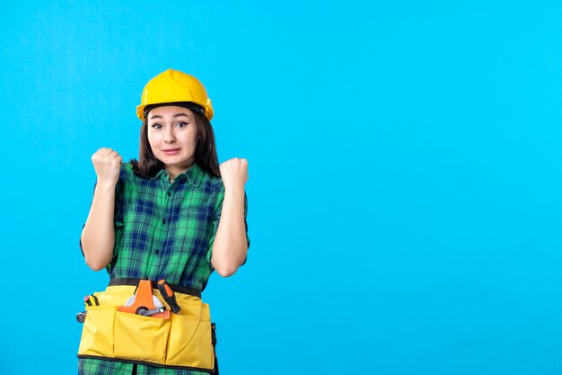 Constructor femenino de vista frontal en uniforme y casco regocijándose en azul