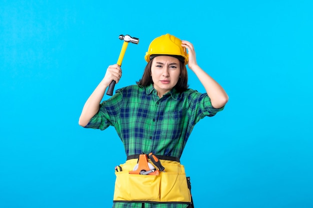 Constructor femenino de la vista frontal en uniforme que sostiene el martillo en azul