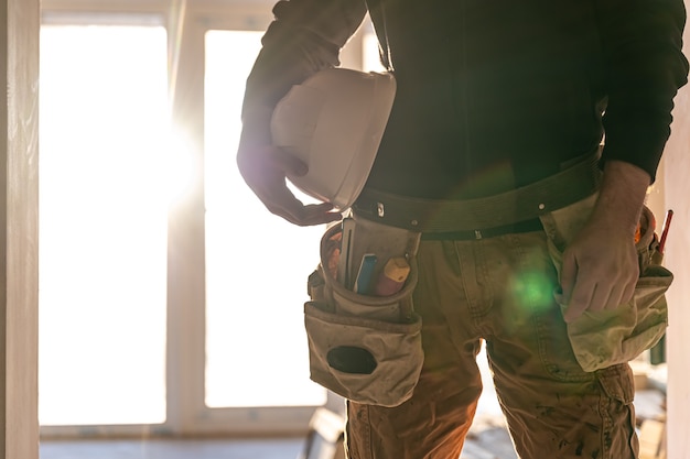 Un constructor de hombre sostiene un casco protector en sus manos, parte del cuerpo.