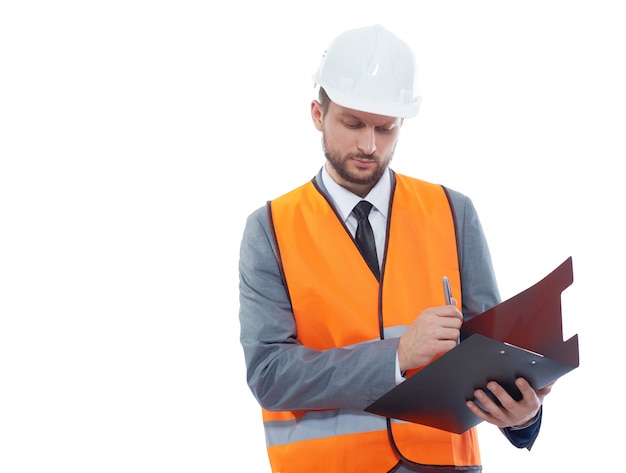 constructor masculino con chaleco fluorescente de seguridad y un casco haciendo notas en su portapapeles aislado en blanco