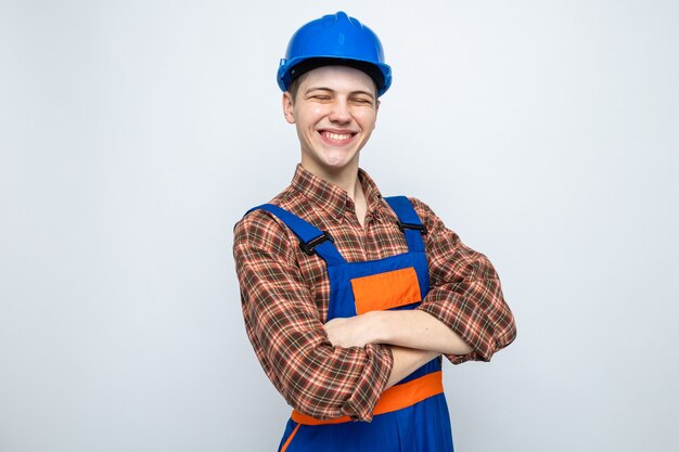 Constructor masculino joven vistiendo uniforme aislado en la pared blanca