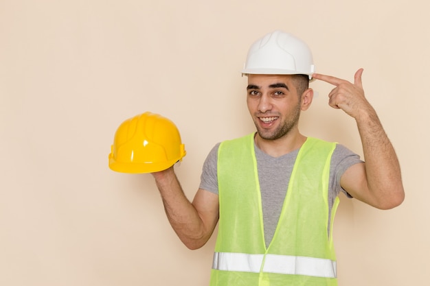 Foto gratuita constructor masculino de vista frontal en casco blanco con casco amarillo en el escritorio de luz