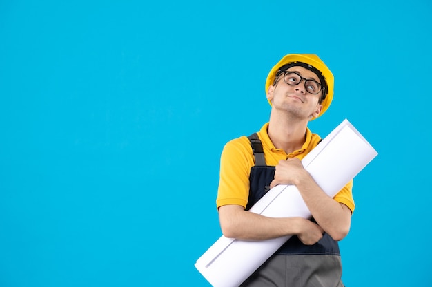 Constructor masculino de vista frontal en uniforme con plan de papel en azul