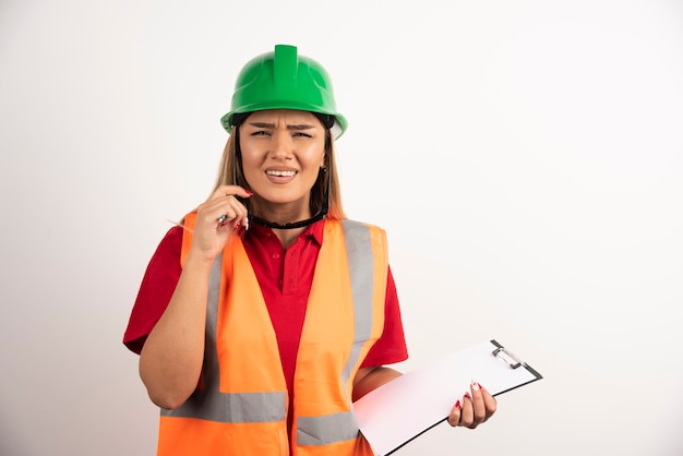 Constructor de mujer joven con gafas con portapapeles.