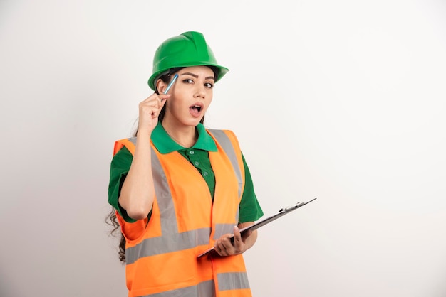 Constructor de mujer preguntando con portapapeles sobre fondo blanco. Foto de alta calidad