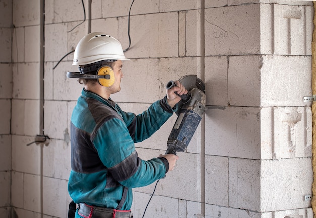 Un constructor profesional con ropa de trabajo trabaja con una herramienta de corte.