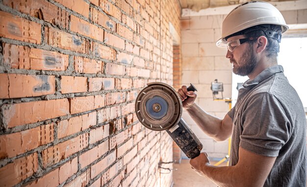 Un constructor profesional con ropa de trabajo trabaja con una herramienta de corte.