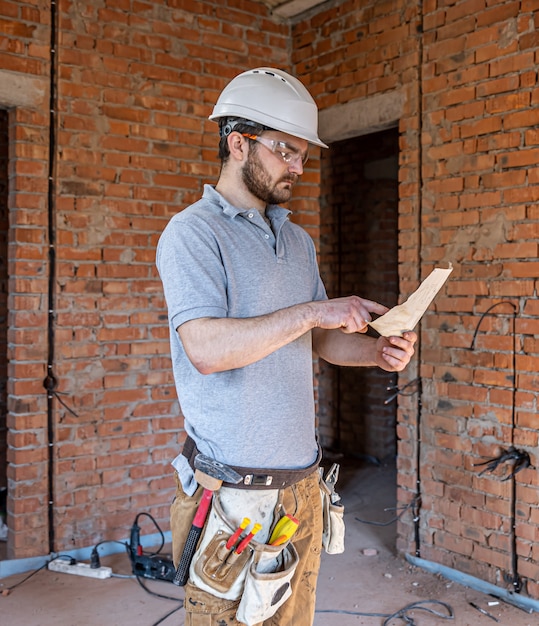 Un constructor en ropa de trabajo examina un dibujo de construcción en un sitio de construcción