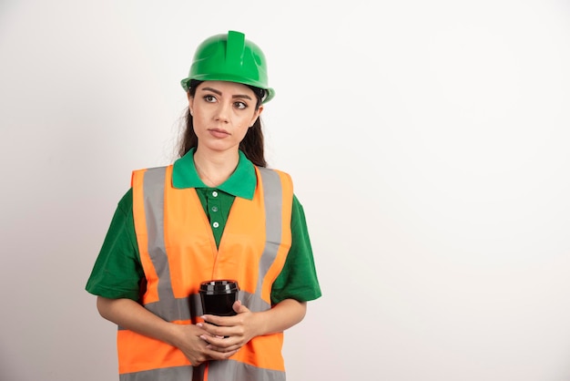 Foto gratuita constructor de sexo femenino joven que sostiene la taza negra y que mira lejos. foto de alta calidad