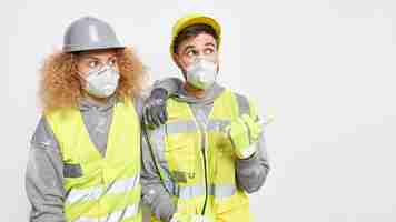 Foto gratuita constructores de hombres y mujeres con cascos de seguridad, respiradores y ropa de trabajo están juntos