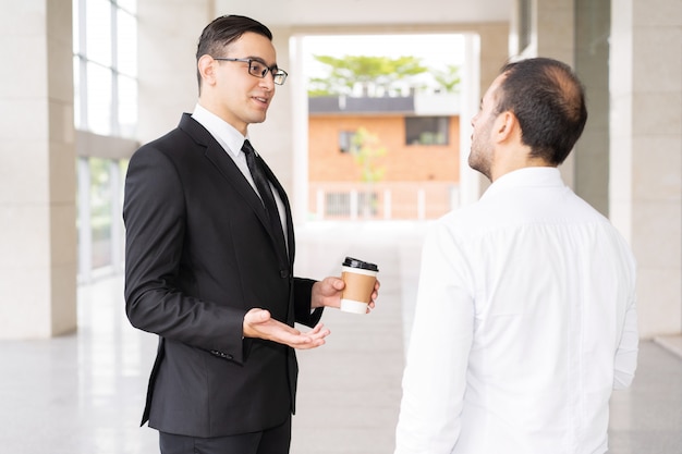 Consultor joven confidente hablando con el cliente en el pasillo de la oficina