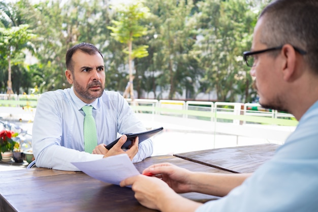 Consultor de negocios explicando papeles al cliente hispano.