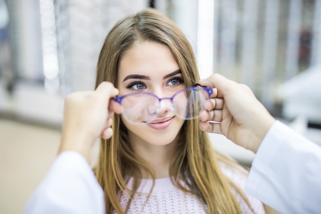 Consultor profesional ayuda a su cliente a elegir gafas médicas en una tienda moderna