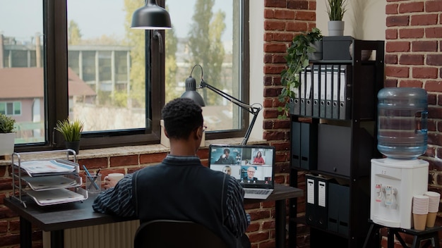 Contador hablando con colegas en videollamadas en línea en la oficina. Consultor financiero que utiliza videoconferencia remota para conversar con compañeros de trabajo sobre estrategia comercial, planificación de proyectos de inicio.