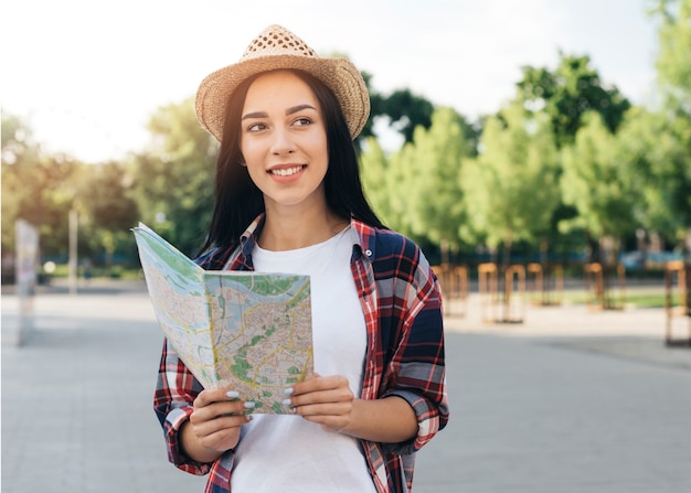 Contemplando a joven sonriente con mapa en la calle