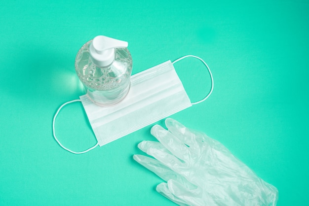 Contenedor con gel de alcohol, guantes y mascarilla quirúrgica en azul claro.