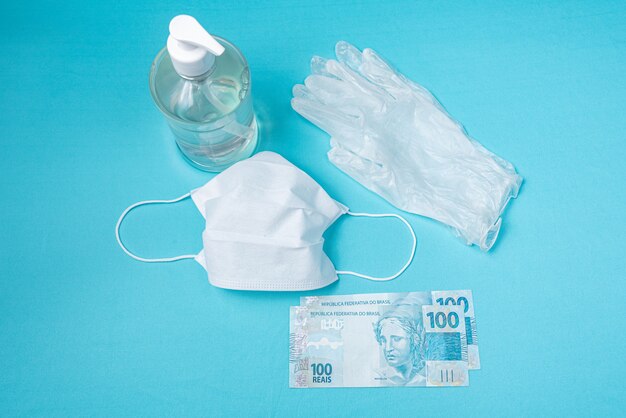 Contenedor con gel de alcohol, guantes, mascarilla quirúrgica y dinero real brasileño,