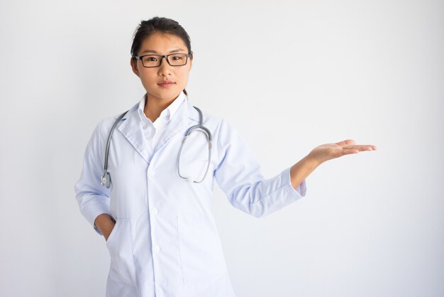 Contenido asiático joven doctora con espacio vacío en la palma.