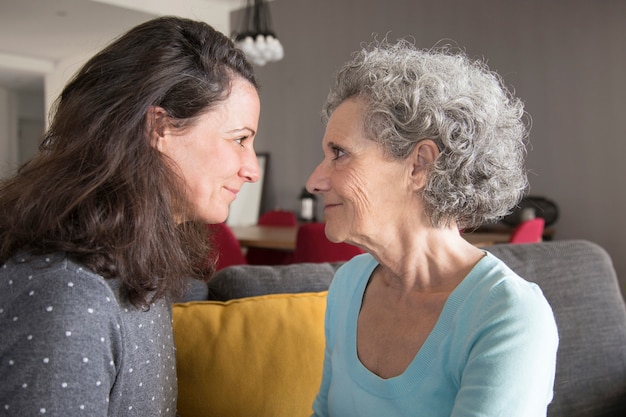 Contenido de la hija adulta tranquila y madre senior mirando a los ojos