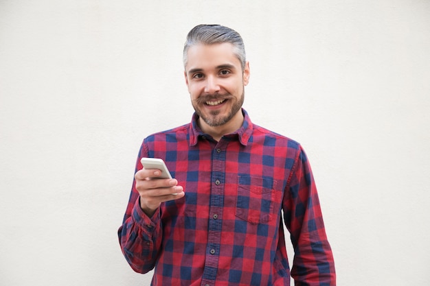 Contenido hombre sosteniendo smartphone y sonriendo