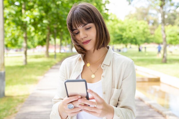 Contenido joven usando teléfono inteligente al aire libre