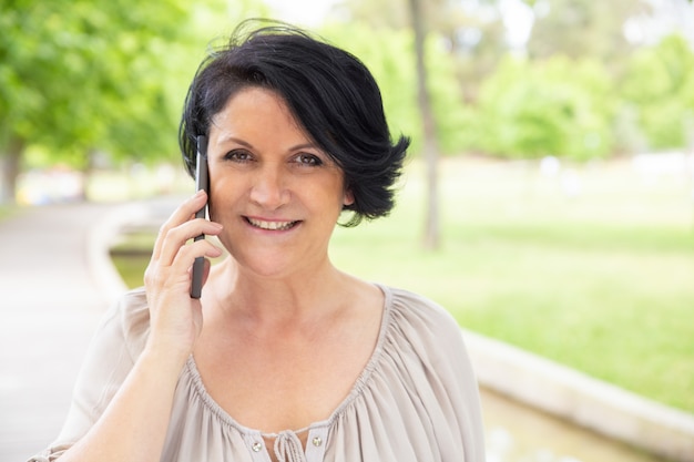 Contenido mujer hablando por teléfono inteligente al aire libre